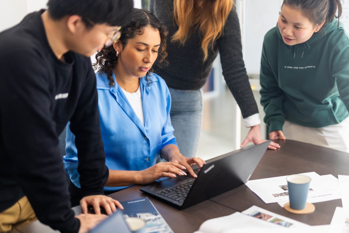 Four member of the Futuretheory team gathered around a laptop, brainstorming Off-Page SEO strategies.